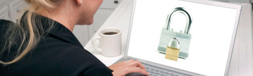 A person uses a smartphone to sign in to a website displayed on a computer monitor, entering login credentials on both devices.