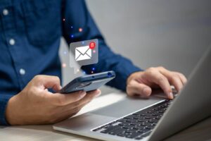 A man is using a laptop with an email icon on it.