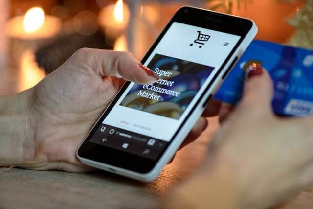 Person holding a smartphone displaying an online shopping site and a credit card, suggesting an online purchase—ideal for businesses looking to boost sales with reliable web hosting Singapore solutions.