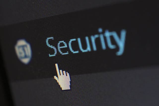 A computer screen displays the word "Security" next to a shield icon, with a pixelated cursor hand pointing at the text—highlighting the importance of web hosting Singapore in safeguarding online data.